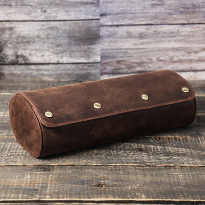 Brown leather watch case cylindrical pouch with metal studs on a wooden surface
