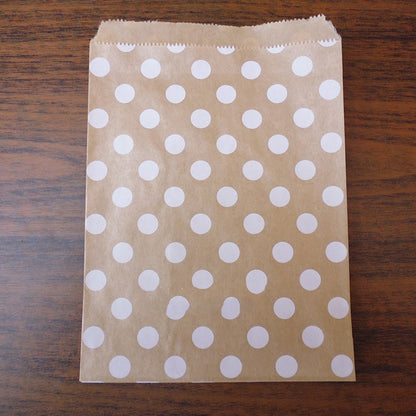 Brown paper bag with white polka dots on a wooden surface