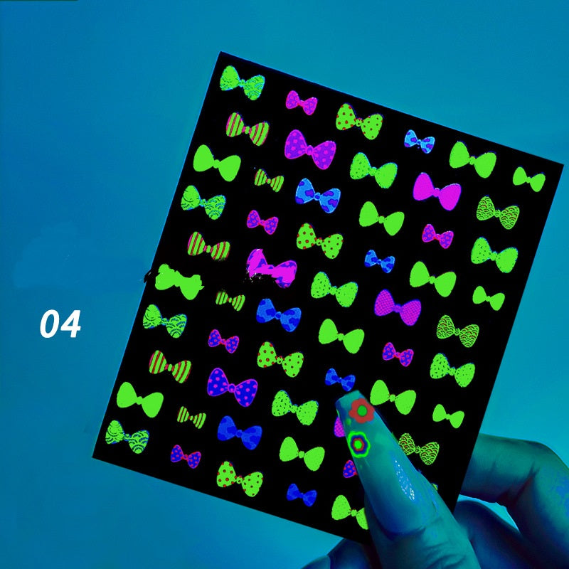 Sheet of colorful bow-tie stickers on a black background with a hand holding it.