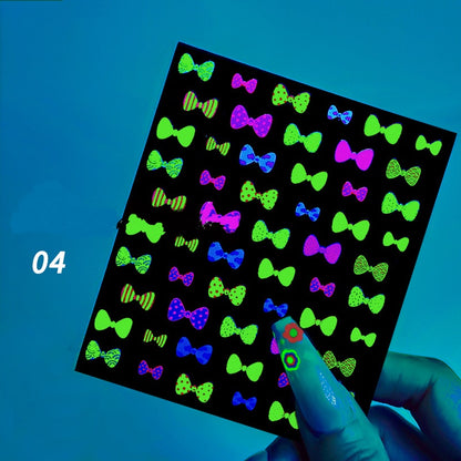 Sheet of colorful bow-tie stickers on a black background with a hand holding it.
