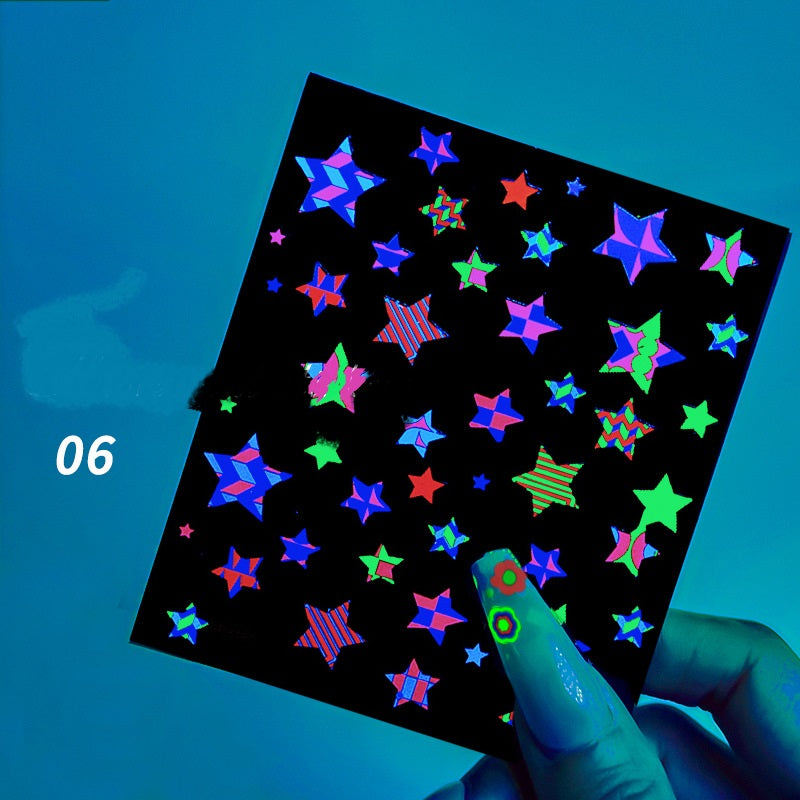 Sheet of colorful star-shaped stickers on a black background, held by a hand with neon green nail polish.