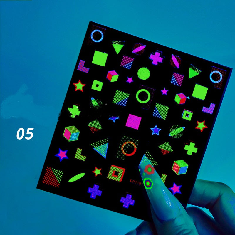 Sheet of stickers with colorful geometric shapes held by a hand against a blue background.