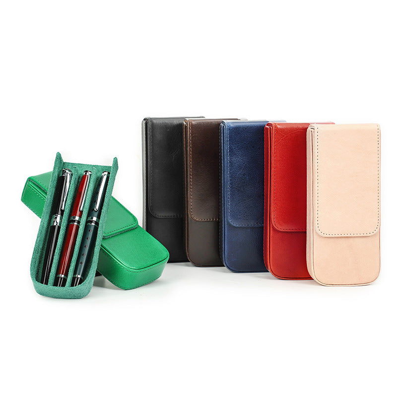 Set of colorful leather cases with pens in a green holder on a white background