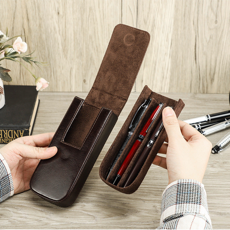 Brown leather pen holder with pens on a wooden surface
