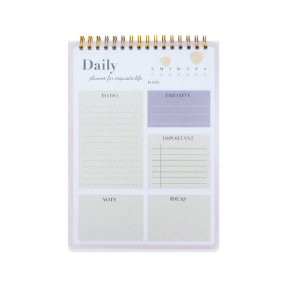 A daily planner desk pad with a white cover, gold spiral binding, and pastel-colored sections for to-do lists, priority, date, notes, and ideas.