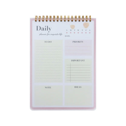 A daily planner notepad with a gold spiral binding, featuring pastel pink and cream sections for to-do lists, priority, date, notes, and ideas.
