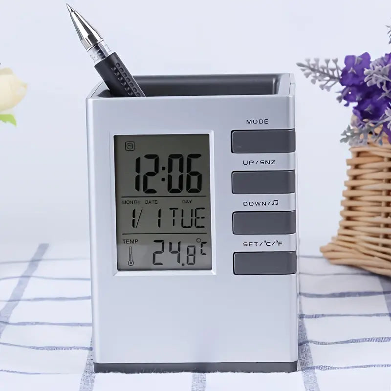 Digital clock with pen holder on a table with flowers in the background